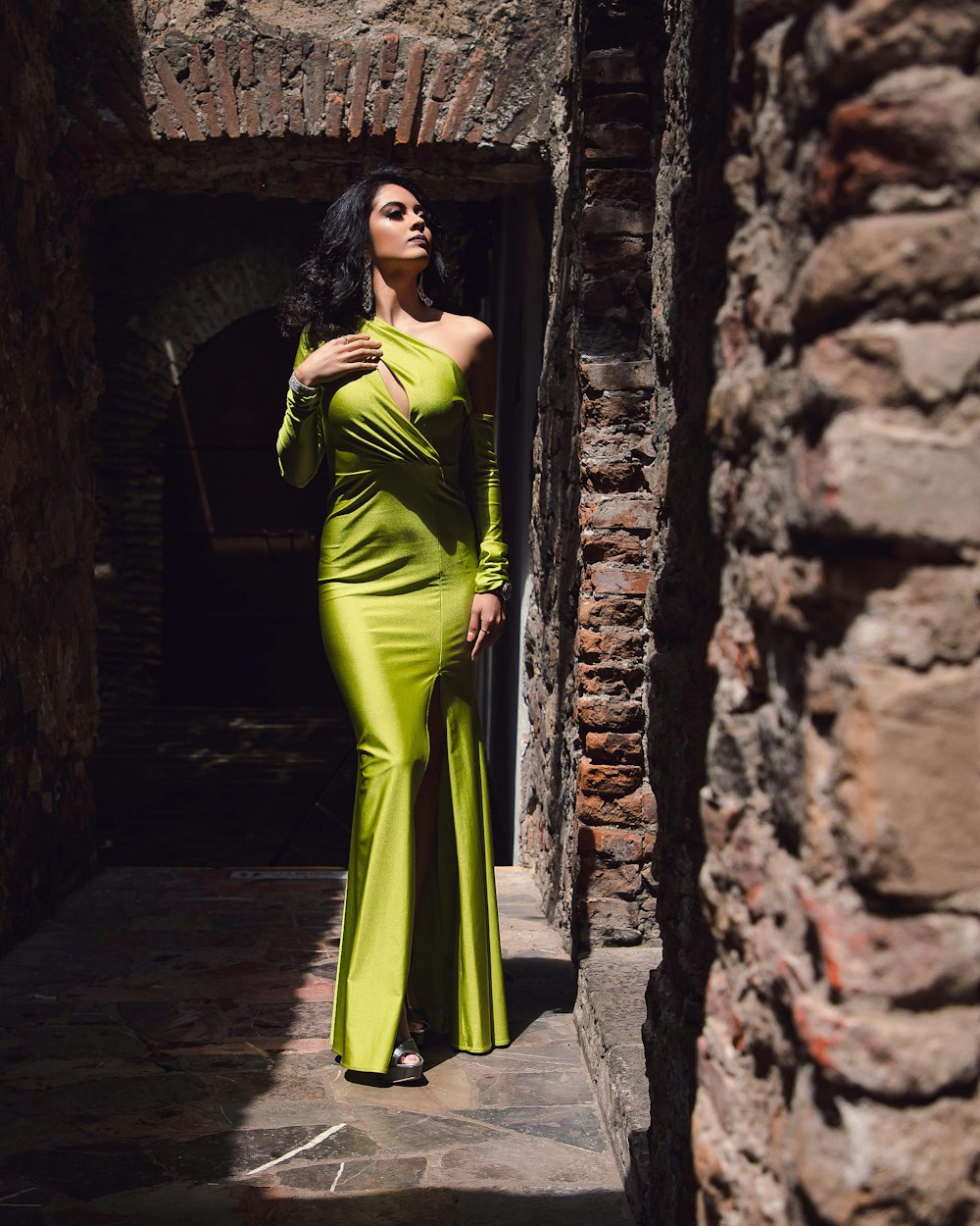 woman in green sleeveless dress standing on brown concrete brick