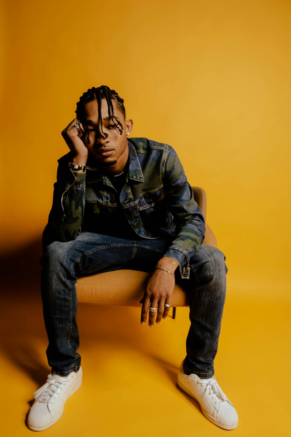 man in black leather jacket and blue denim jeans sitting on yellow chair