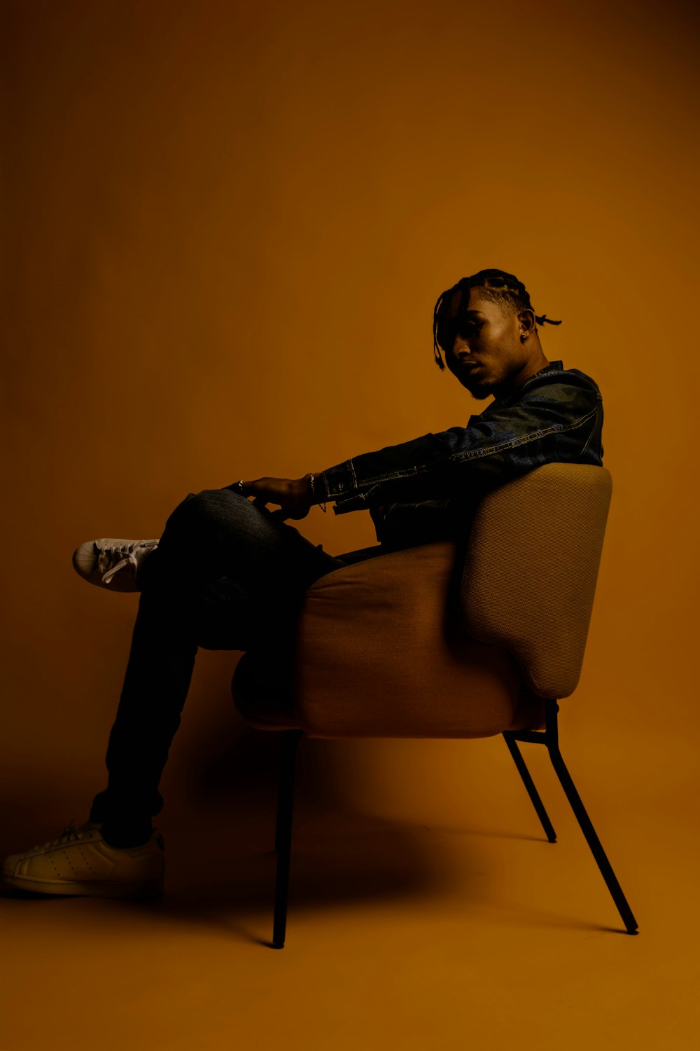 man in black jacket sitting on yellow chair