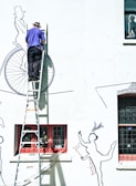 man in blue jacket and blue denim jeans riding bicycle