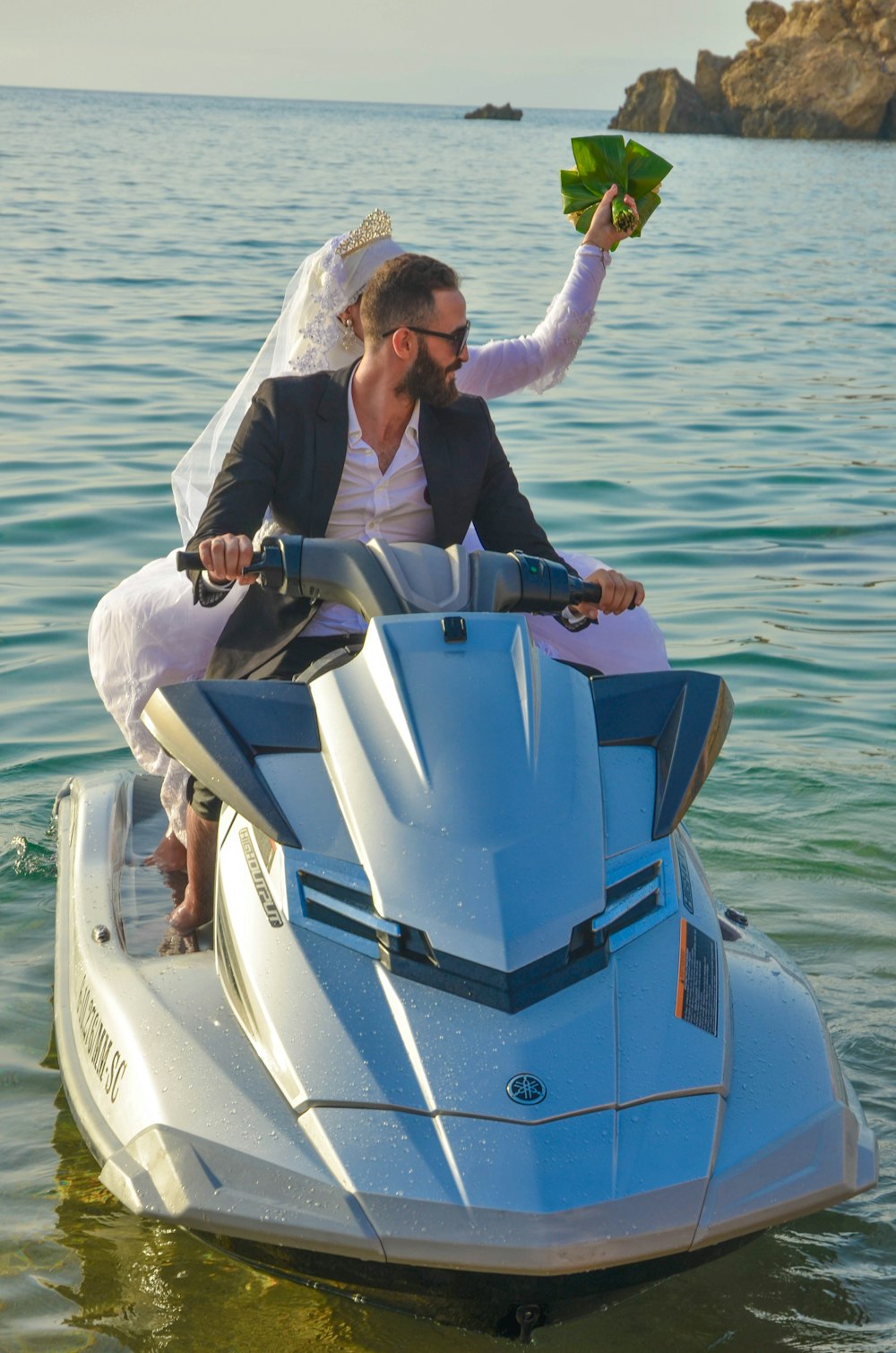 man in gray jacket riding white and blue personal watercraft