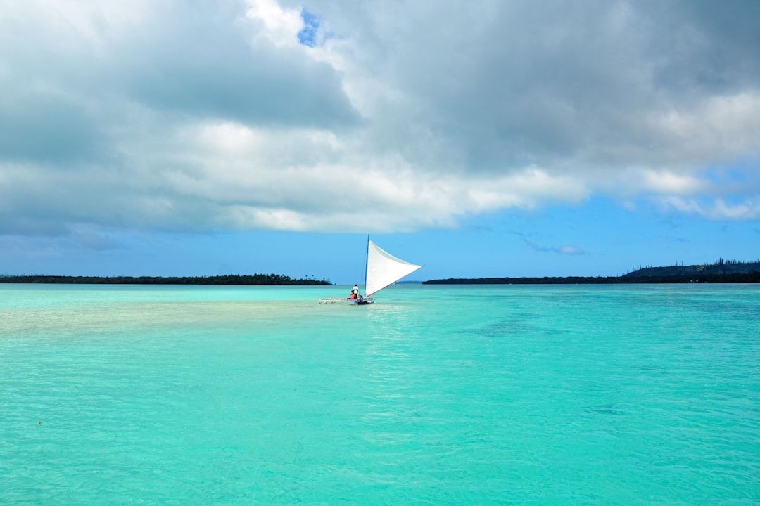 white sail boat on sea under white clouds during daytime