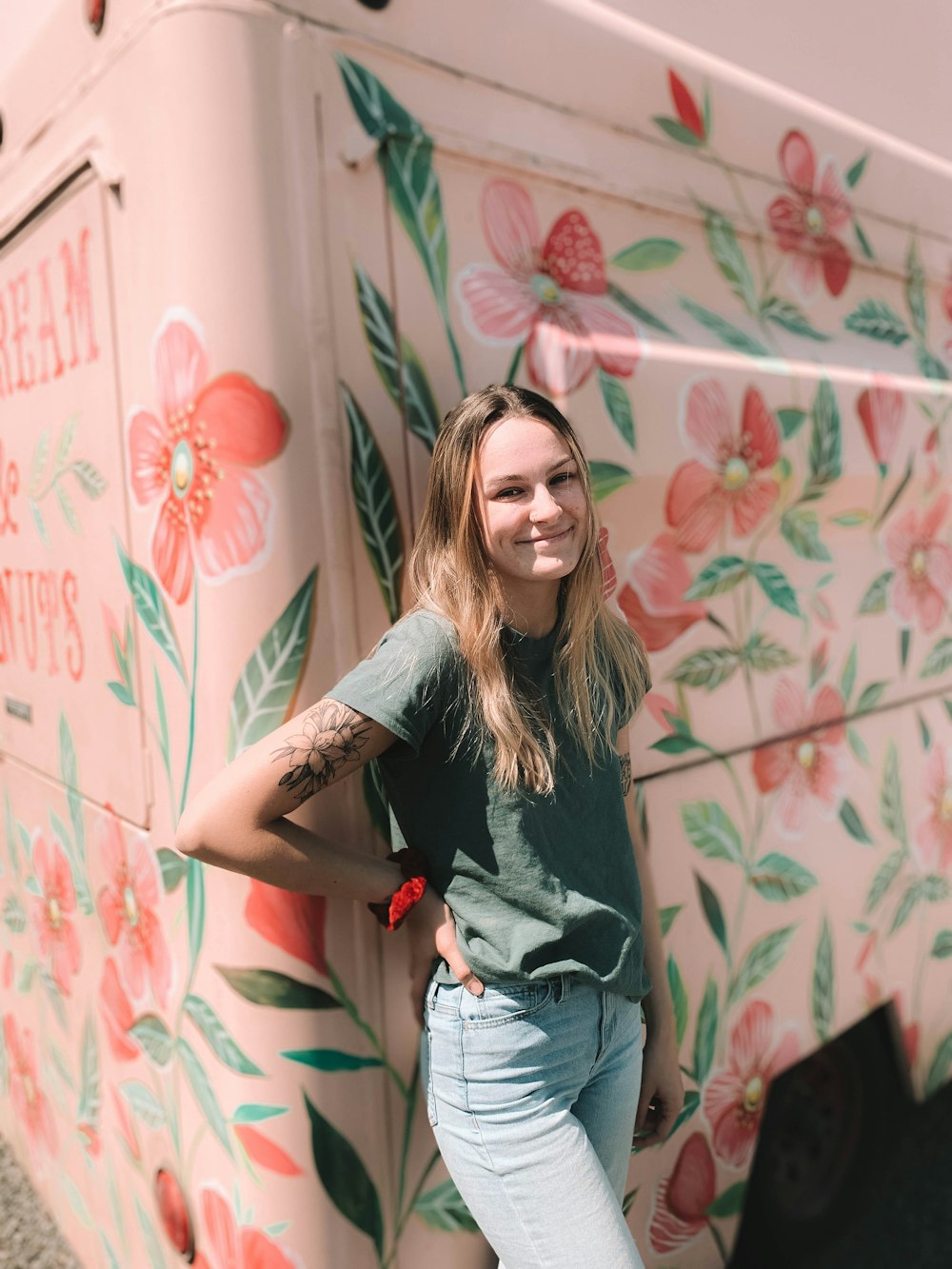 woman in gray t-shirt and blue denim jeans standing beside wall with graffiti