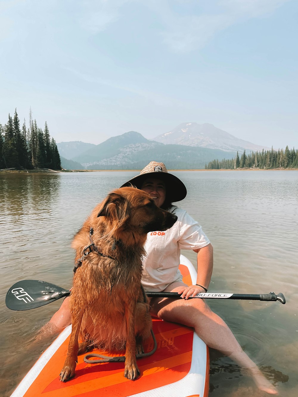 man in white shirt and black shorts sitting on red kayak on lake during daytime