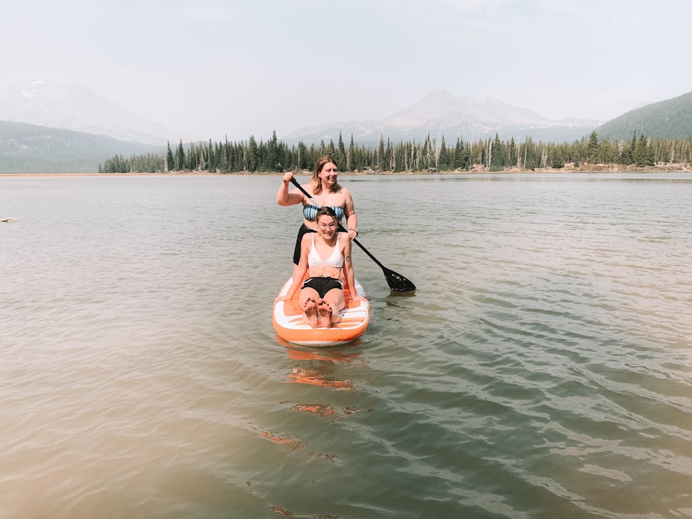 woman in black bikini riding on brown boat on body of water during daytime