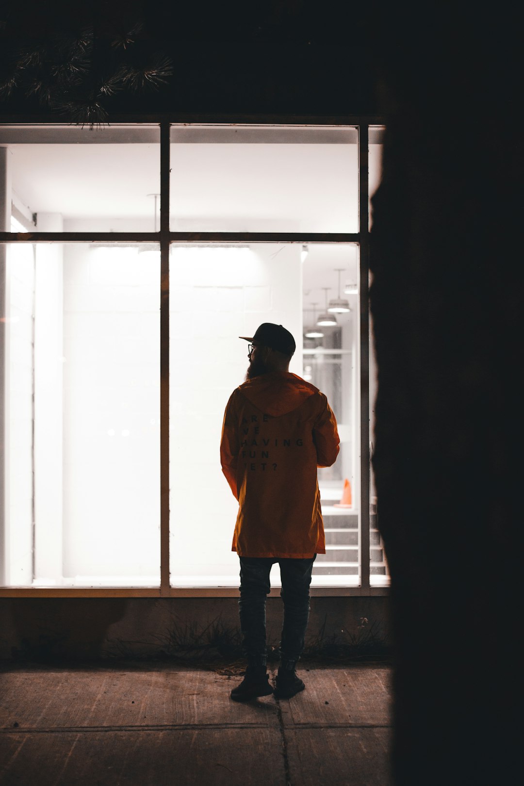 man in brown jacket standing in front of window