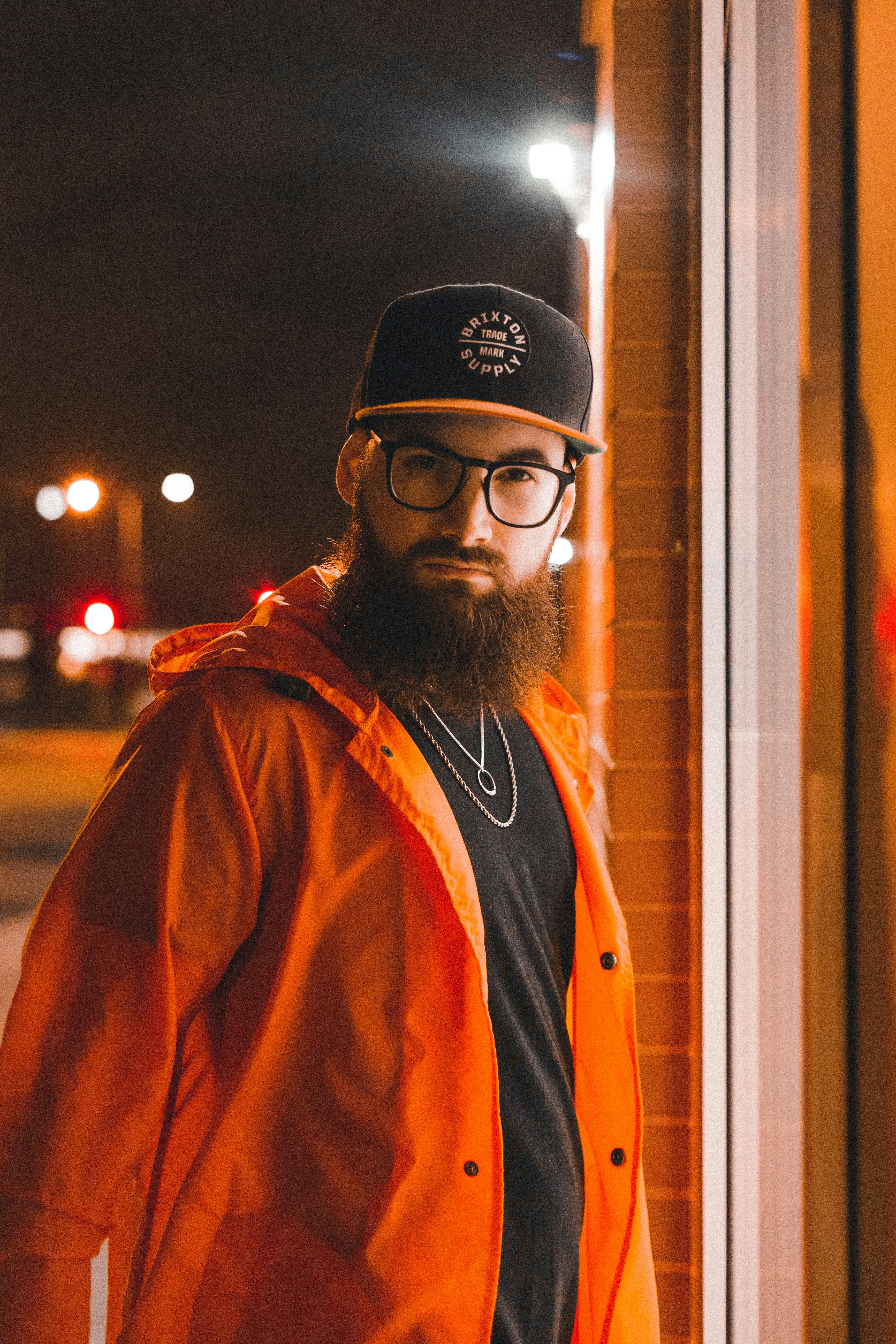 man in black knit cap and orange jacket