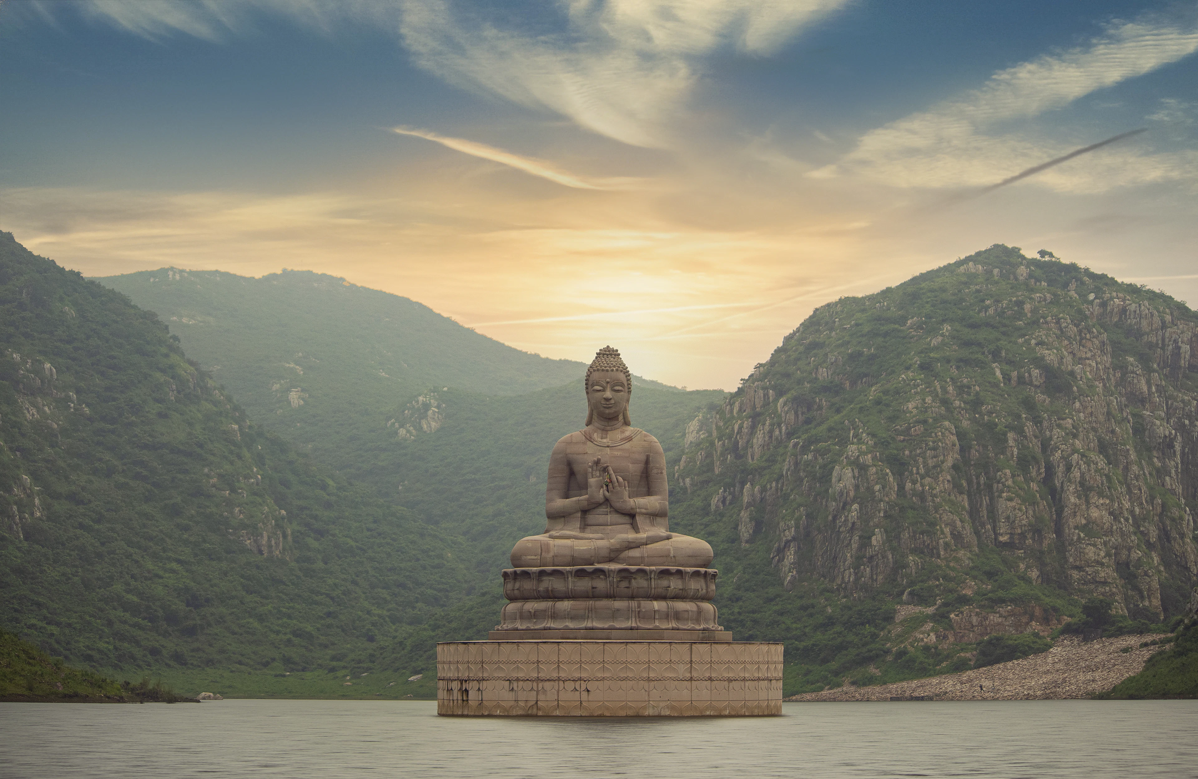 Brown Buddha statue near green mountain under blue sky during daytime