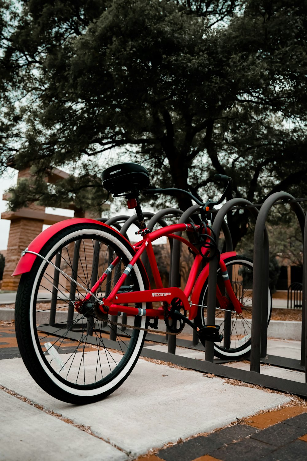 red and black bicycle parked beside brown wooden fence during daytime