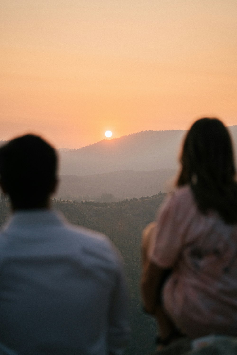 man and woman standing on field during sunset