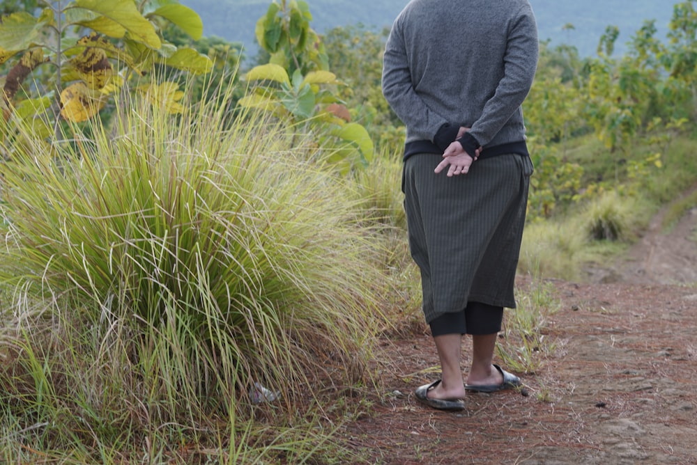 woman in gray blazer and black skirt walking on pathway between green plants during daytime