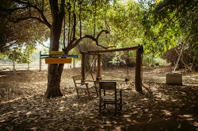 A cozy wooden porch swing with plush Sunbrella cushions gently swaying under a shaded veranda.