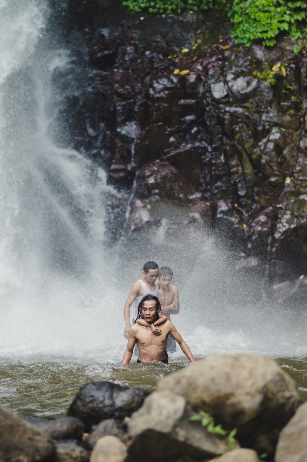 2 women sitting on rock in water