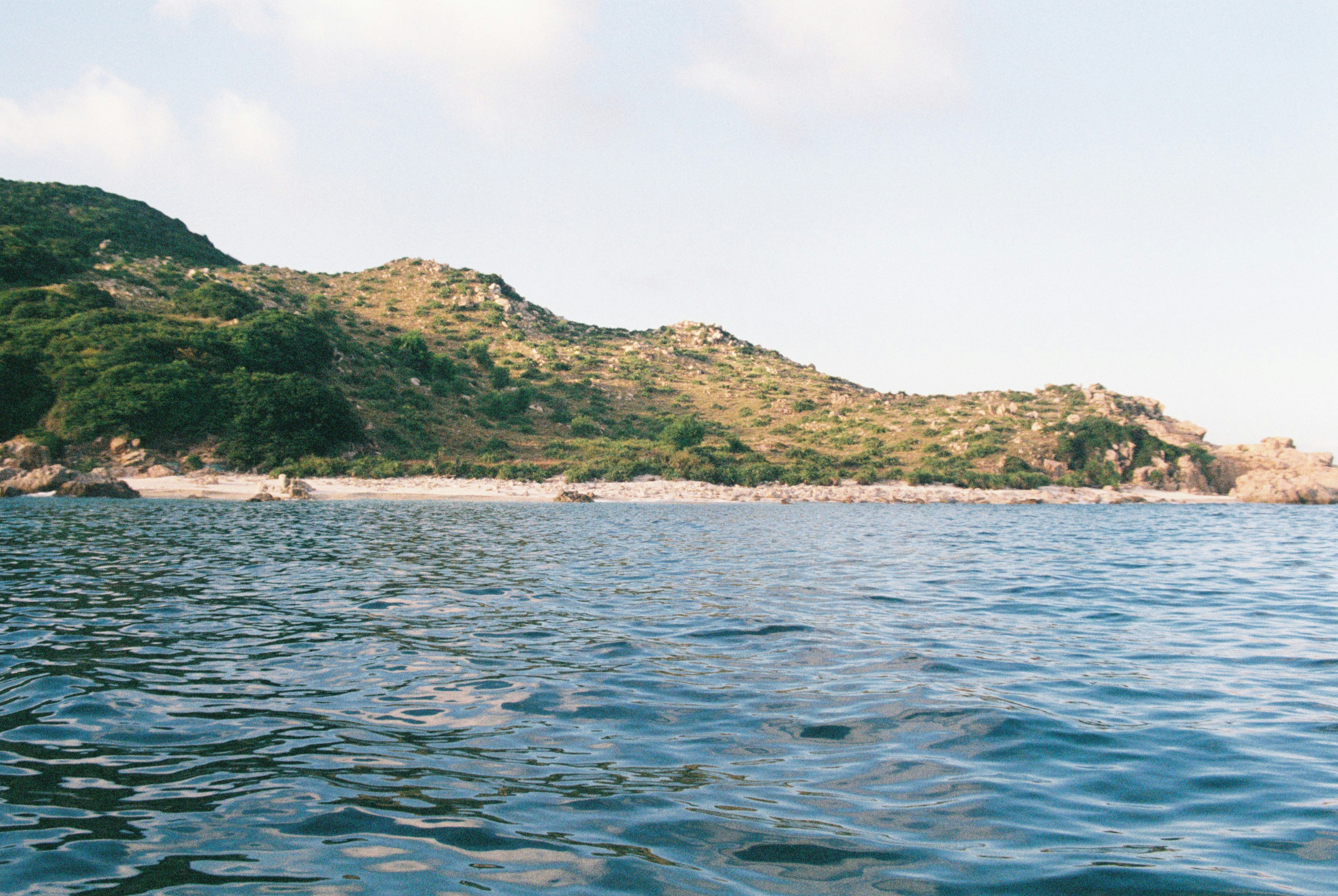 Green mountain beside body of water during daytime photo – Free Beach ...