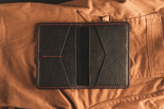 black leather bifold wallet on brown textile