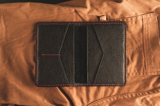 black leather bifold wallet on brown textile