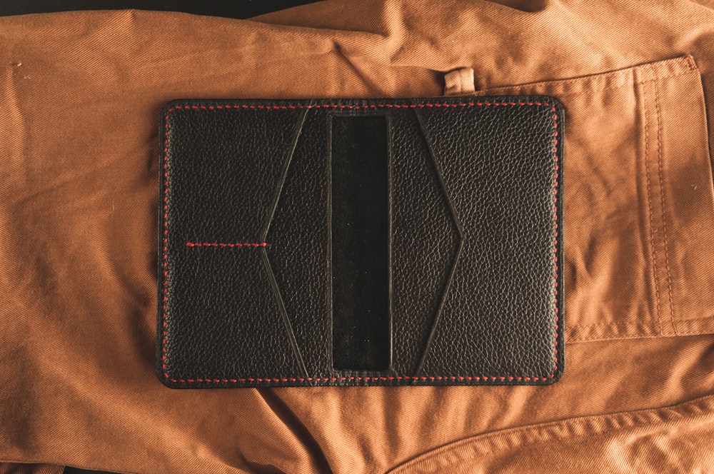 black leather bifold wallet on brown textile