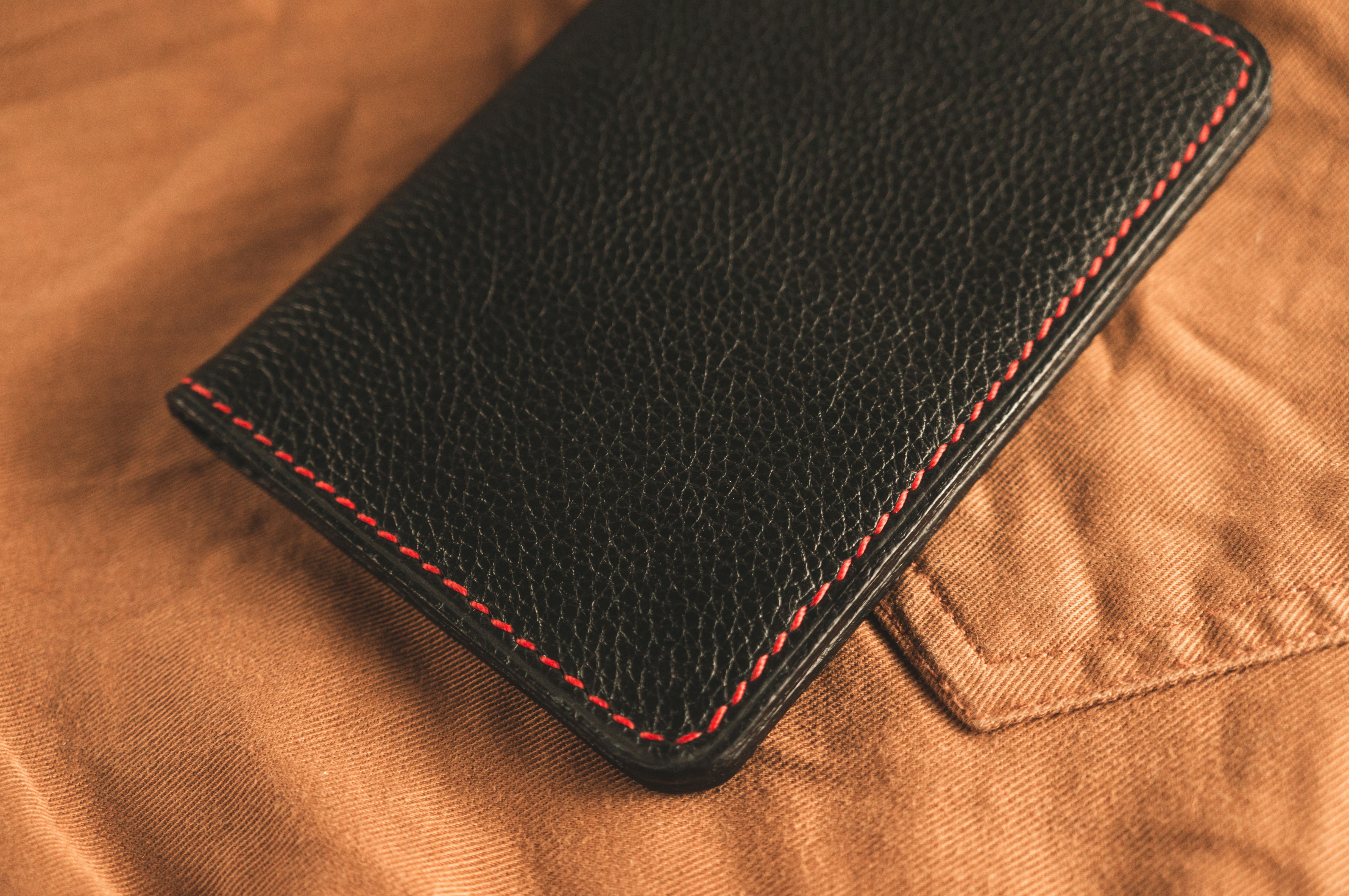 black leather bifold wallet on brown textile