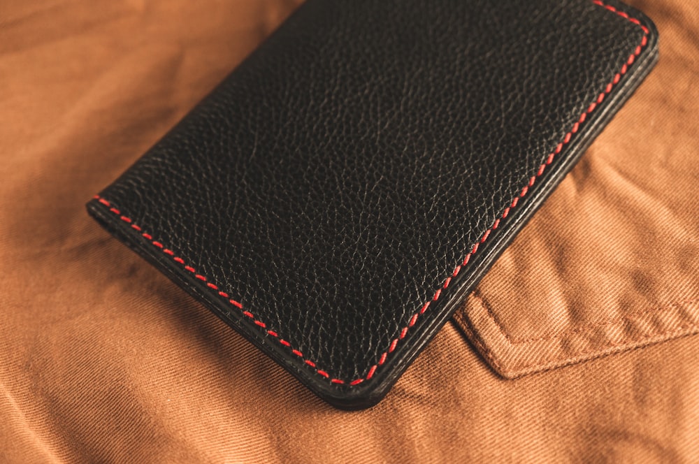 black leather bifold wallet on brown textile