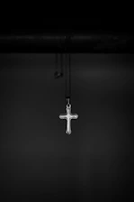 Close-up of the x chain necklace highlighting its sleek X-shaped pendant on a minimalist black background.