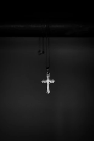Close-up of the x chain necklace highlighting its sleek X-shaped pendant on a minimalist black background.