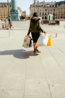 woman in black jacket and white skirt walking on sidewalk during daytime