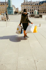 woman in black jacket and white skirt walking on sidewalk during daytime