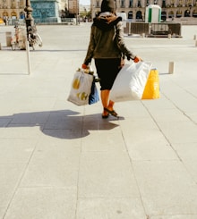 woman in black jacket and white skirt walking on sidewalk during daytime