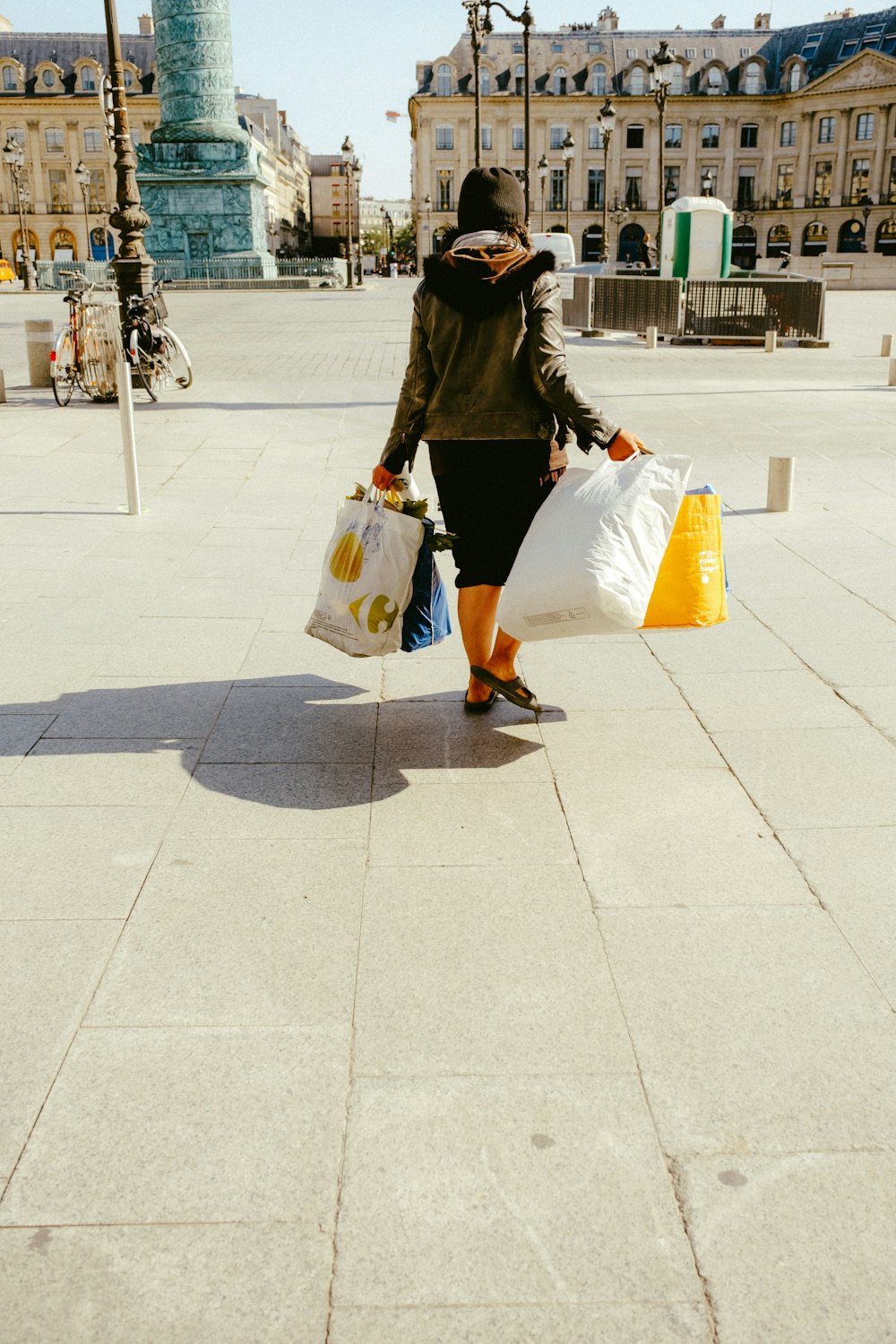 woman in black jacket and white skirt walking on sidewalk during daytime