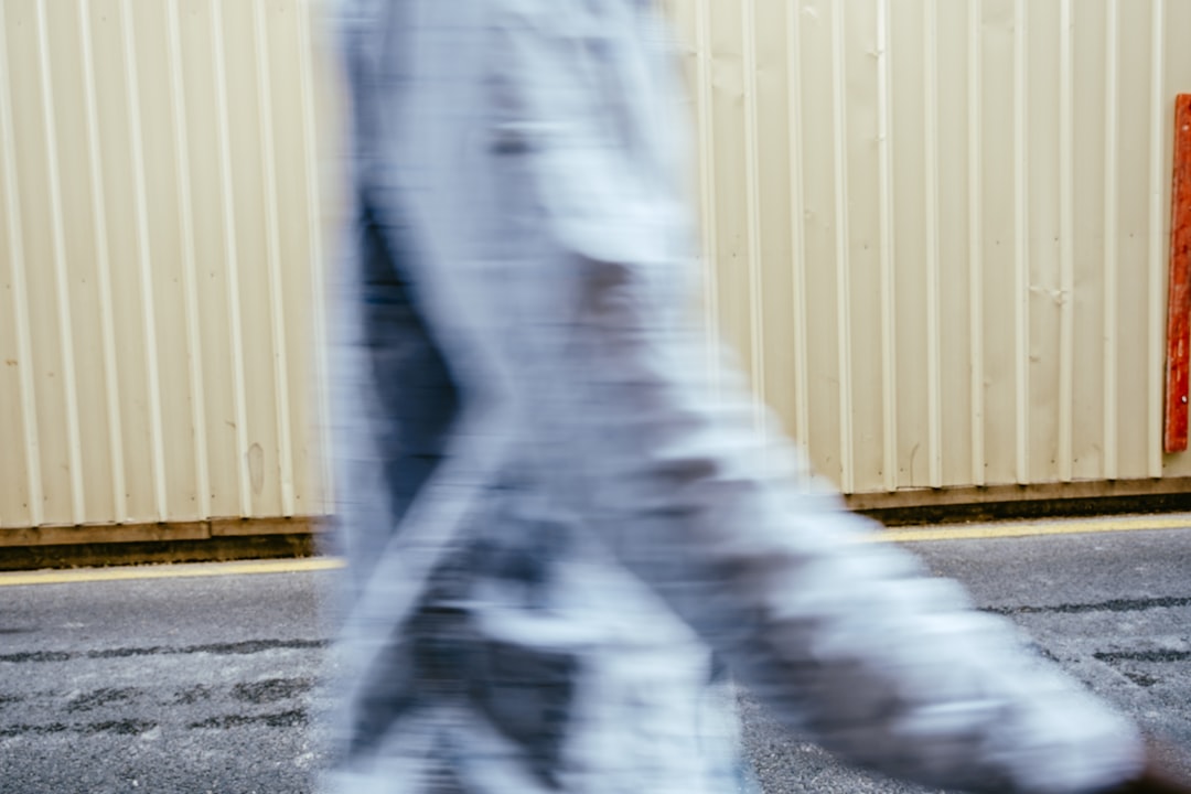 person in white and black pants standing near white wall