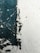 Peeling paint on a wall reveals a rough texture beneath. The paint is dark green in some areas, creating an abstract and weathered appearance against the lighter wall surface.