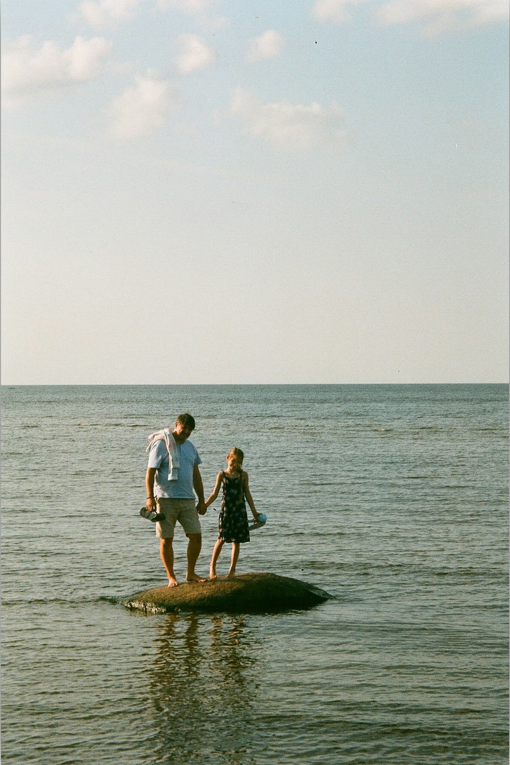 uomo e donna in piedi sulla roccia in mezzo al mare