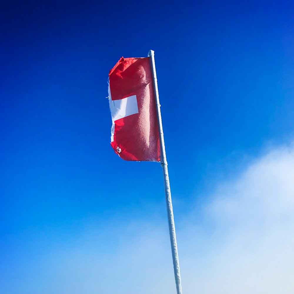 red and white flag on pole under blue sky during daytime