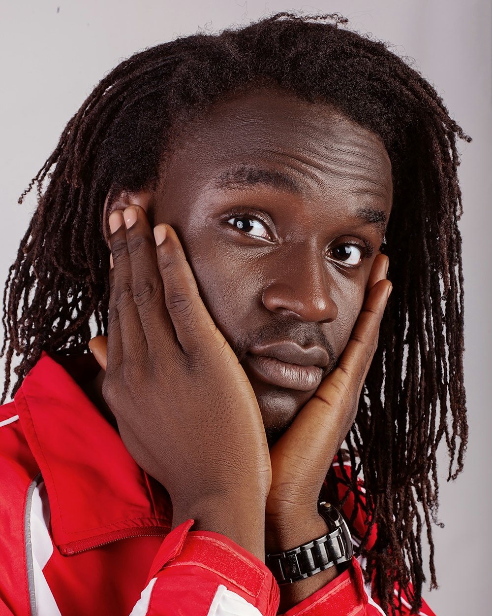 woman in red and white collared shirt covering her face with her hand