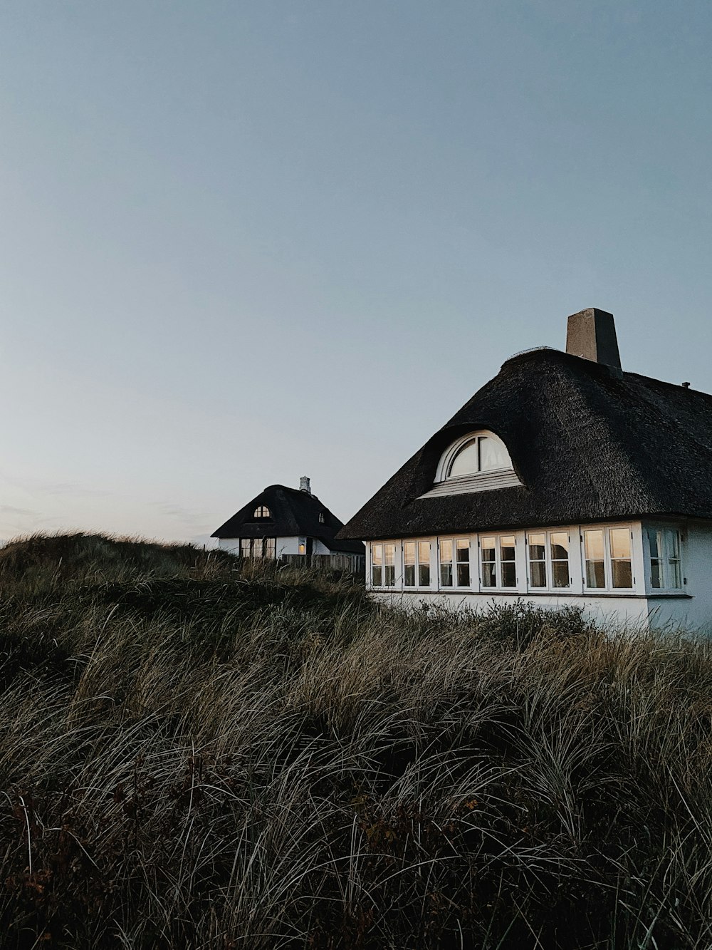 white and brown house on green grass field under gray sky