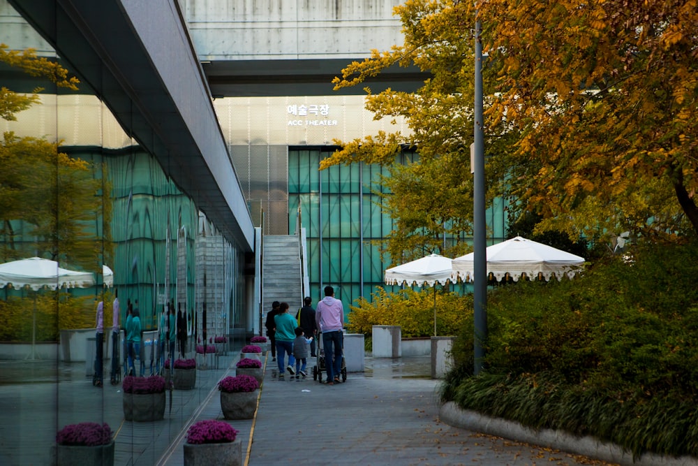 Menschen, die tagsüber auf dem Bürgersteig in der Nähe von Green Building spazieren gehen