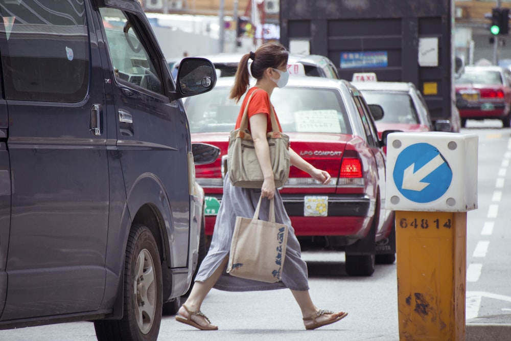 woman in white dress holding white plastic bag standing beside black car during daytime