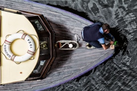 man in blue t-shirt and black pants sitting on brown wooden boat