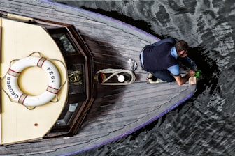 man in blue t-shirt and black pants sitting on brown wooden boat