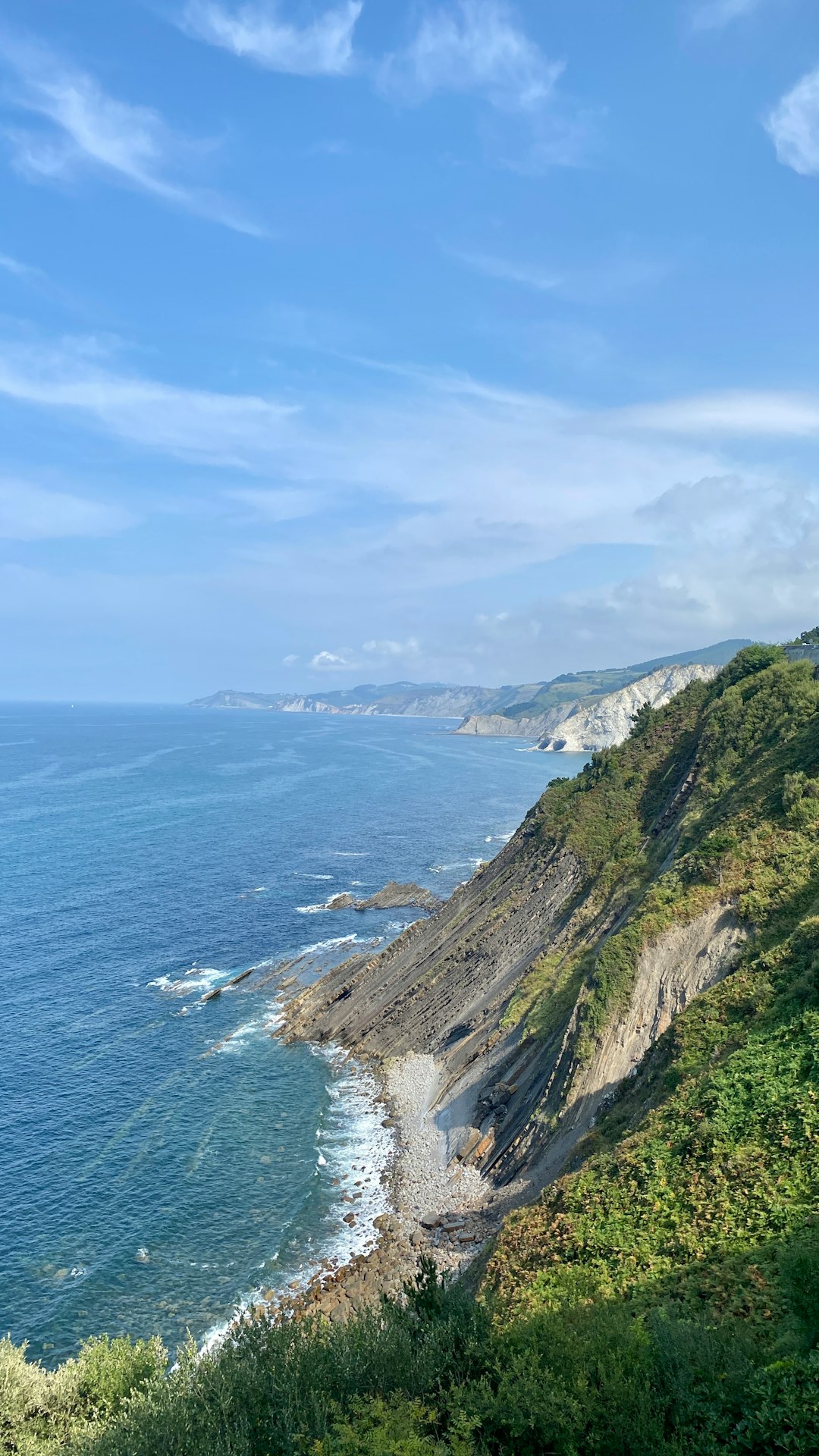 green and brown mountain beside body of water under blue sky during daytime