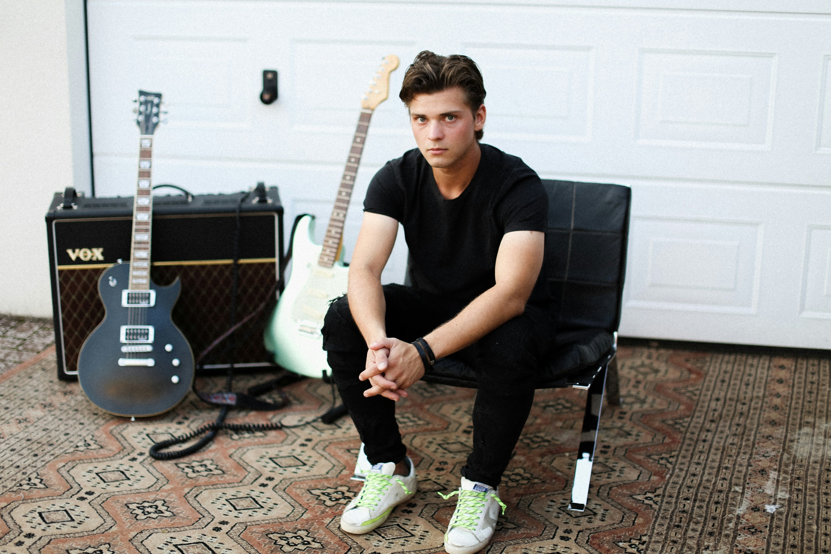 man in black crew neck t-shirt and black pants sitting on black and white electric