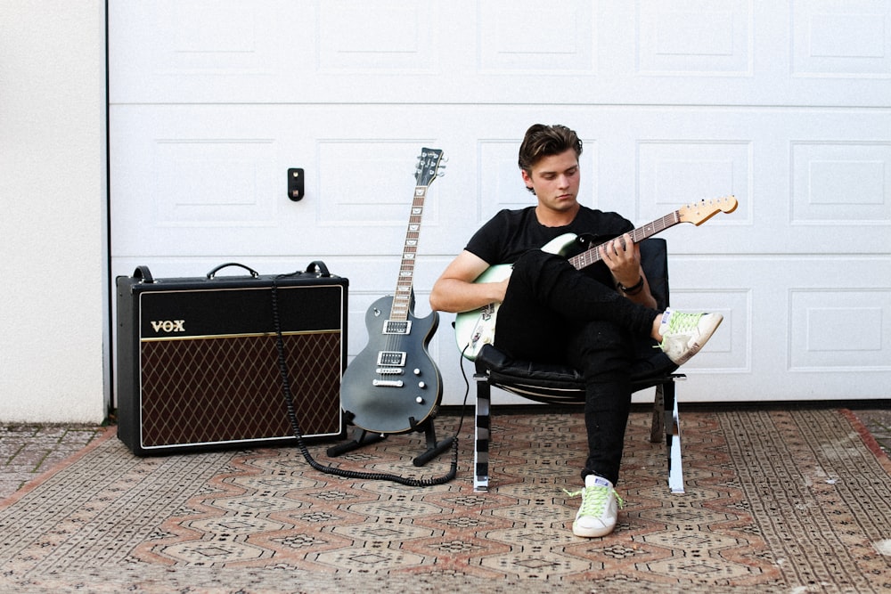 man in black crew neck t-shirt playing guitar