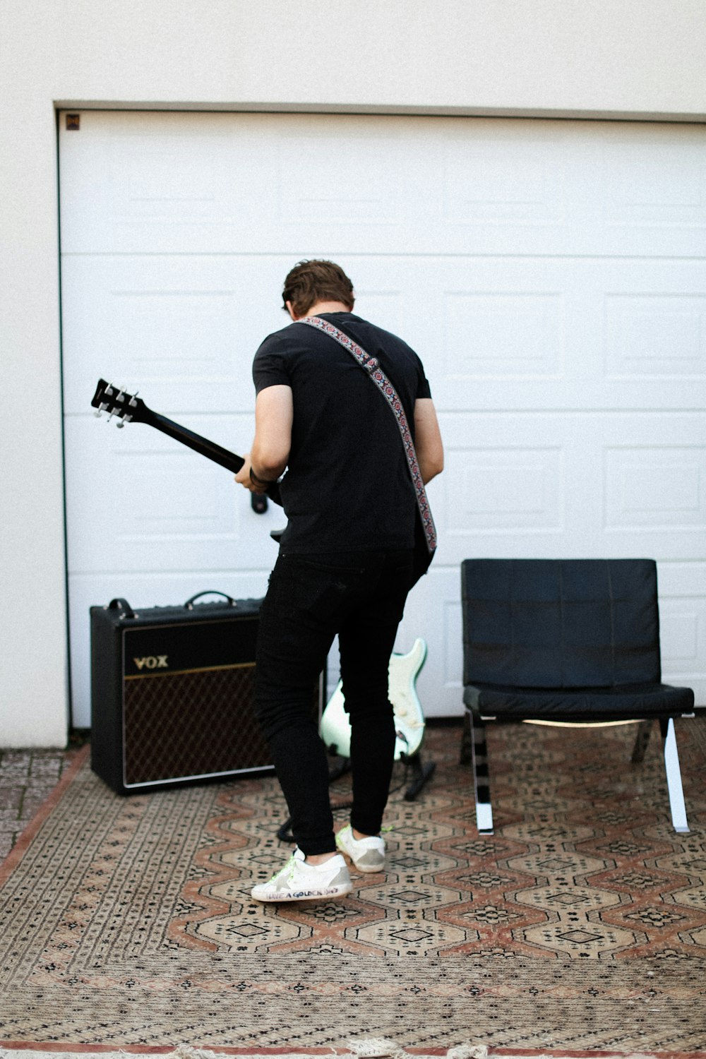 man in black tank top and black pants standing beside black guitar amplifier