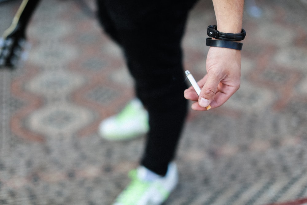 person in black long sleeve shirt holding cigarette stick