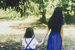 2 women in blue dress standing on green grass field during daytime