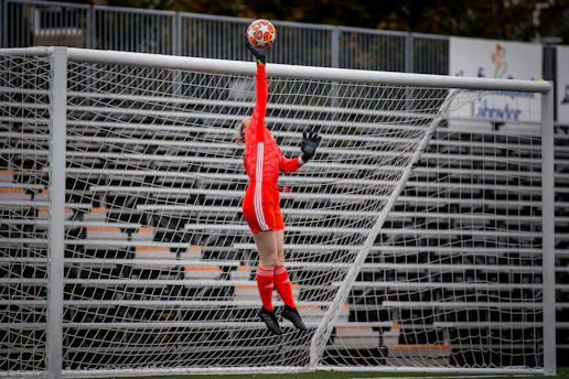 man in red jersey shirt and black pants playing soccer