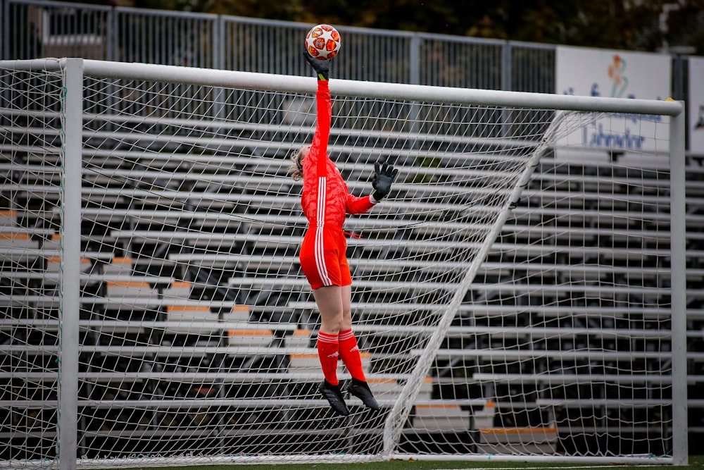 man in red jersey shirt and black pants playing soccer