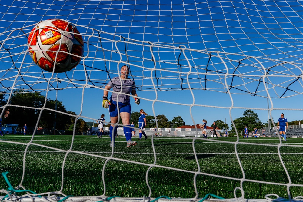 man in blue and white stripe shirt holding red and blue soccer ball