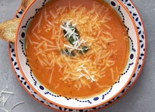 orange soup on white and blue ceramic bowl