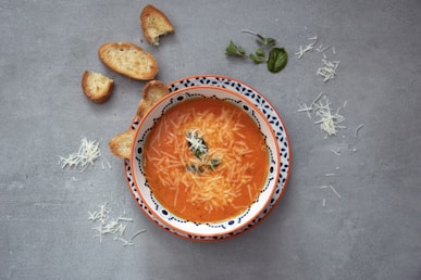 orange soup on white and blue ceramic bowl